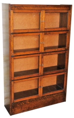 An early 20thC oak bookcase, with four pairs of glazed doors enclosing shelves, raised on a plinth base, 130cm high, 81cm wide, 24cm deep.