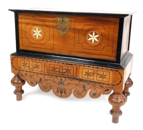 A 19thC Dutch Colonial fruitwood and ebonised campaign chest, the boxed top with a hinged lid, ornate brass estrucheon plate and bone inlaid flowers, the base with three frieze drawers inlaid in ebony and bone with flower motifs above a shaped frieze, sim