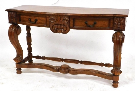 A Colonial style mahogany bow fronted side table, with floral carving, two frieze drawers, raised on front scroll supports united by a shaped stretcher, 72cm high, 122cm wide, 45cm deep.