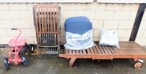 A teak sun lounger, two similar deck chairs, and a garden seat in red, on four wheels.