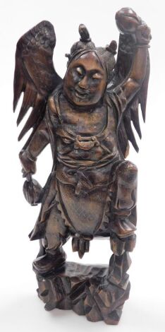 A Balinese hardwood and silver wire inlaid figure, of a Garunda, modelled standing with wings aloft and holding two gourds, 43cm high.