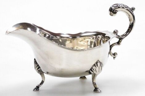 A George V silver gravy boat, with a shaped rim and open handle, on three hoof leaf capped legs, Jay, Richard Attenborough Co Ltd, Sheffield 1921, 7.63oz, 11cm high.