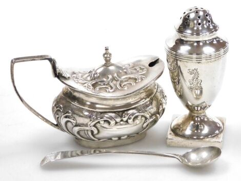 A Victorian silver pounce pot, of urn form with an engraved crest, on a square base, Birmingham 1882, 7.5cm high, and an Edward VII silver mustard pot, with embossed scroll decoration, blue glass liner, with associated mustard spoon, Birmingham 1905, 3.10