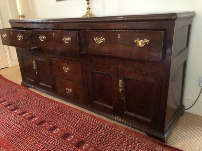 A George III oak dresser base, with moulded top, three drawers over two central drawers, flanked by two panelled doors, all with replacement brass swan neck handles, and bracket feet, 85cm high, 186cm wide, 52cm deep. - 2