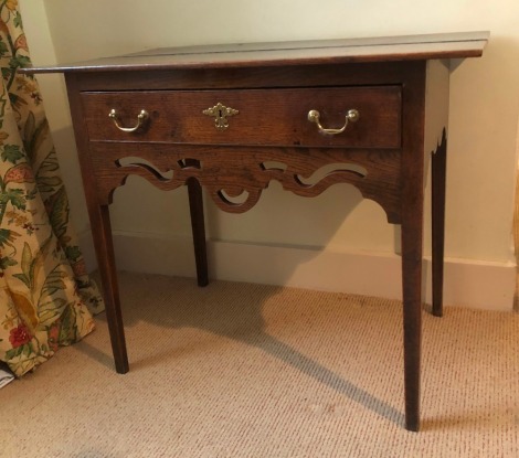 A George III oak lowboy, with over hanging rectangular two plank top, single frieze drawer with brass handles, and fret work carved frieze, on square taper legs, 72cm high, 86cm wide, 54cm deep.