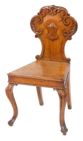 A Victorian oak hall chair, with a foliate carved balloon and shield back, solid seat, raised on cabriole legs.