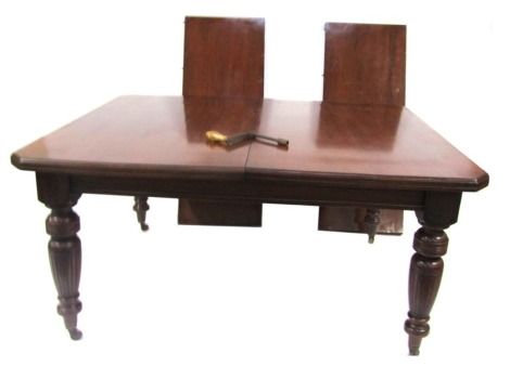 A Victorian mahogany wind out dining table, with one additional leaf, raised on turned legs, brass capped on castors, 73cm high, 146cm wide extended, 121cm deep.