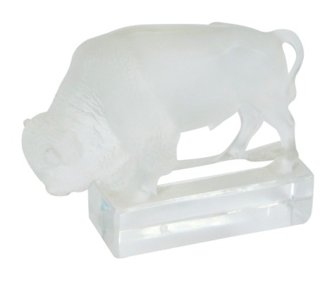 A Lalique glass figure of a bison, modelled standing with its head down on a rectangular base, etched mark, 12cm wide. (AF)