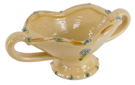 A Fenella Mallalieu studio pottery centre bowl, on a fluted and flared top, on a turquoise and mustard ground, with four point crested flower design, shaped handles, unmarked, 13cm high, 30cm diameter.