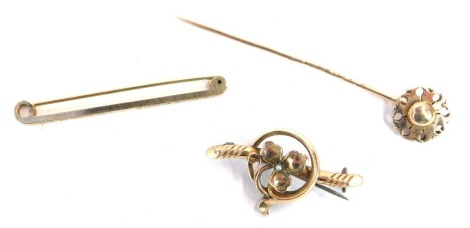 A group of jewellery, comprising a 9ct gold floral scroll topped stick pin, a bar brooch with central circular emblem and three leaf clover with cultured pearl, and a bar brooch of etched design, 7.5g. (3)