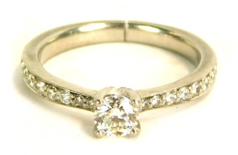 A diamond dress ring, with round brilliant cut in four claw setting, approx 0.25ct, with tiny diamond set shoulders on a white metal band, unmarked, believed to be platinum, size N, cut, 5.4g all in.