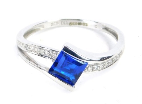 A 9ct white gold dress ring, with central dark blue square cut stone in tension setting, with tiny diamond set shoulders, 2.1g all in.