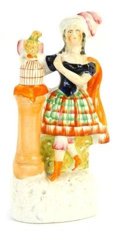 A Staffordshire flat back figure of a Scottish lady, with plinth and bird atop a cage, 24cm high.