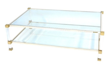 A Pierre Vandel of Paris Hollywood Regency Lucite rectangular coffee table, with bevelled glass top and under tier supported on clear Perspex framing with brass finished decoration, the top 119cm x 69cm.