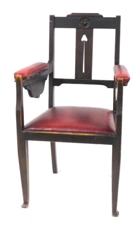 An Arts & Crafts stained pine elbow chair, the pierced tulip splat back, with red leatherette arms and seat, 100cm high, 56cm wide.