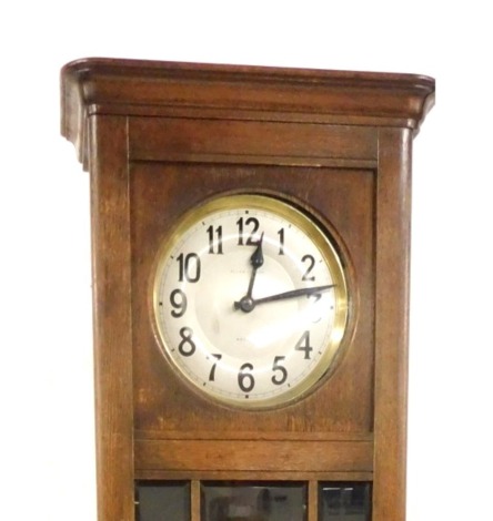 Allan Gibson of Nelson. An early 20thC oak longcase clock, circular silvered dial bearing Arabic numerals, the case inset with nine bevelled rectangular and square glass panels, above a floral carved panel, raised on block feet, with pendulum and weights,