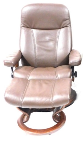 A Stressless brown leather single reclining armchair and footstool, with additional arm table.