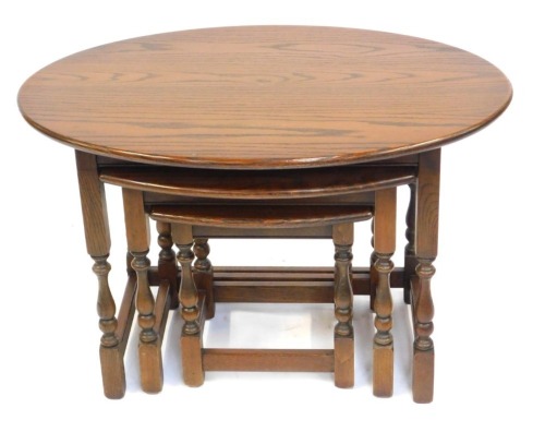 A nest of three Old Charm oak tables, each with an oval top, the largest 53cm high.