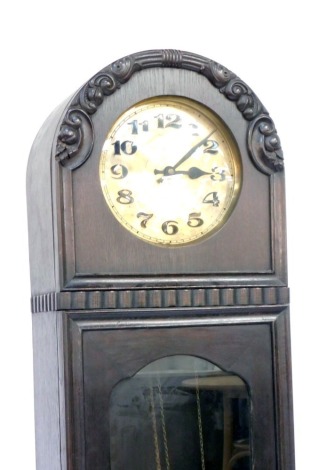 A late 19thC stained pine longcase clock, the arched top with a concave glass plate and a brass numeric dial, with two weights and pendulum.