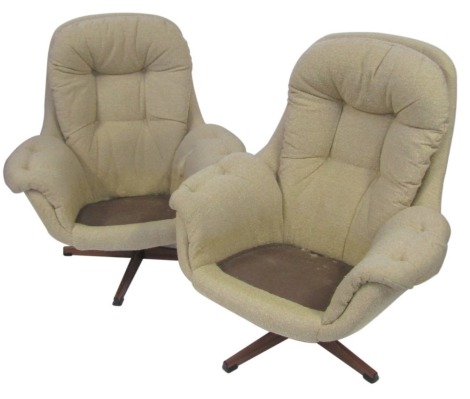 A pair of retro material egg chairs, each with cream material on rosewood style metal base. The upholstery in this lot does not comply with the 1988 (Fire & Fire Furnishing) Regulations, unless sold to a known exporter or upholsterer it will be cut from 