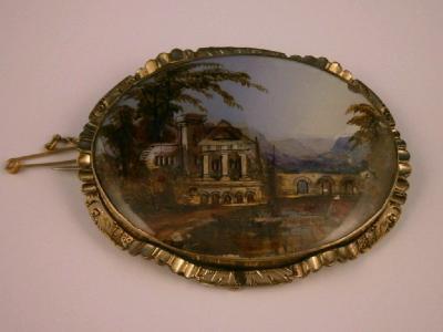 A Victorian oval brooch of an Italianate landscape with gilt highlights