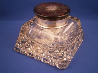 A cut glass inkwell with a tortoiseshell and silver mount