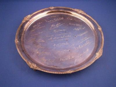 A circular silver salver with a decorative leaf cast edge