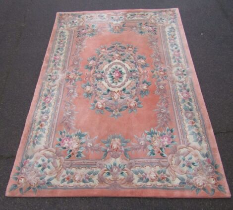 A Chinese wool cut rug, on a pink floral ground, with central and border, 274cm x 183cm.