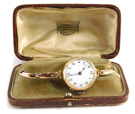 An early 20thC wristwatch, with 3cm diameter Arabic enamel dial in an unmarked 9ct gold case, with elasticated bracelet, in fitted case.