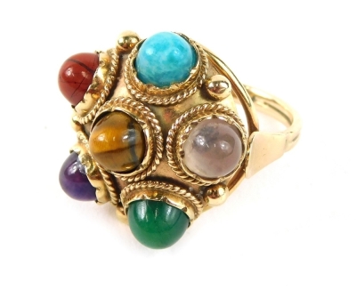 An Eastern inspired multi stone dress ring, of circular form set with turquoise, tigers eye, jade, amethyst, moonstone, and red agate, on a plain band yellow metal stamped 9ct, ring size N½, 7.6g all in.