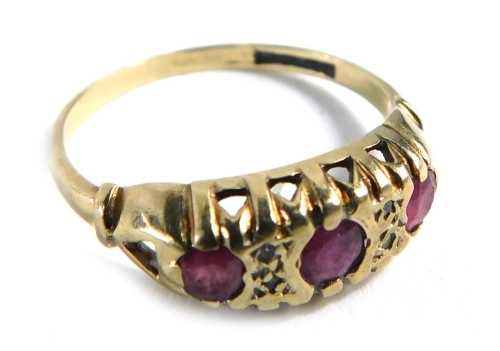 A 9ct gold gypsy ring, set with three rubies in rub over setting, with four tiny diamonds and scroll design shoulders, ring size N½, 1.7g all in.