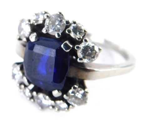 A sapphire and diamond dress ring, rectangular cut sapphire in four claw setting approx 0.35ct, flanked by an arrangement of ten tiny diamonds, white metal wedding band, unmarked believed to be 18ct, ring size O, 5.8g all in.