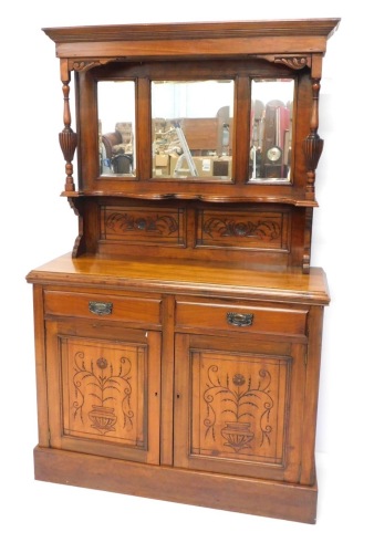 A late Victorian walnut sideboard, the raised back with three bevelled plates, flanked by turned and fluted columns, above a shaped shelf, the base with a moulded edge above two short drawer and two carved panel doors decorated with an urn, on a plinth, t