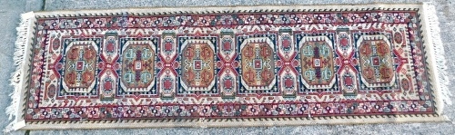 A machine woven runner, with a design of medallions, on a beige coloured ground with one wide border, 136cm x 69cm.