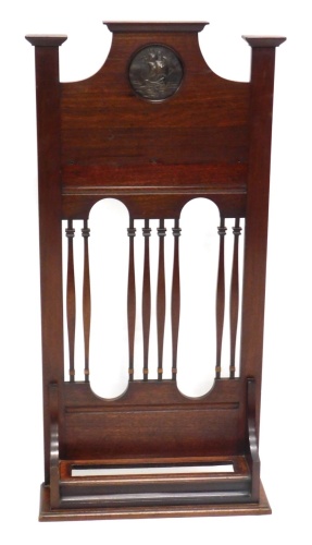 An early 20thC mahogany umbrella stand, with circular metal ship emblem, above pierced centre and rectangular opening beneath, 106cm high, 51cm wide, 16cm deep.