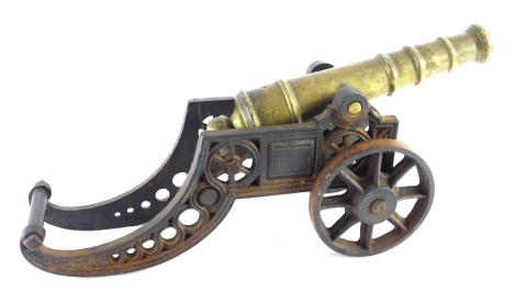 A brass table cannon, on iron truckle base, 20cm high.