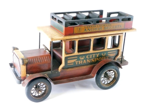 A wooden model of an open top bus, with stencilled advertising and articulated wheels, 35cm high.