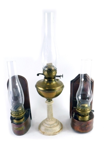 A brass table lamp, with clear glass funnel, brass reservoir and classical column stem, 60cm high, and two copper hanging wall lamps. (3)