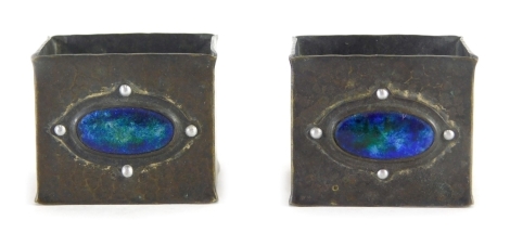 A pair of early 20thC Liberty Tudric style pewter napkin rings, each with hammered bodies and oval green and blue enamel sections, unmarked, 4cm wide.