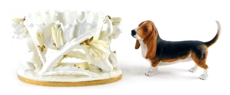 A 19thC Moore and Co centrepiece, the floral bowl held on the shoulders of children, with gilt lined base, marked beneath, 15cm high, and a Royal Doulton figure of a basset hound. (2)