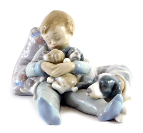 A Lladro figure of a sleeping child, holding puppies aside dog, number 1535, printed and impressed marks beneath, 18cm wide.