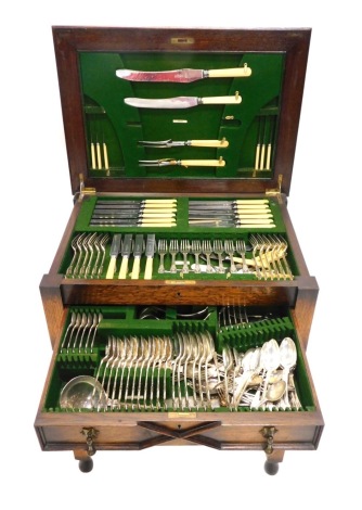 A freestanding oak cased canteen of silver plated cutlery, King's pattern, part settings for six, the canteen on barley twist legs joined by a H stretcher, with front drawer revealing further serving pieces, 80cm high, 64cm wide, 44cm deep.