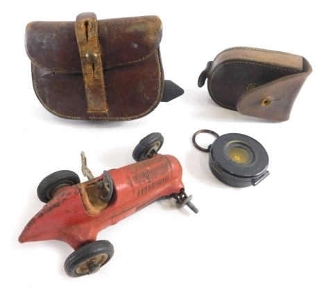 A mid 20thC Schuco studio clockwork racing car, 7cm high (AF), and two pressed leather purses. (3)