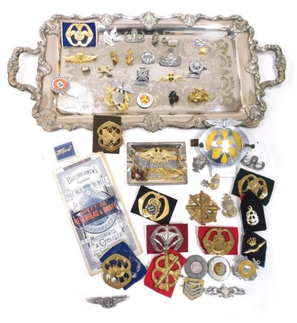 A silver plated tray, 52cm long, various cap badges, metal regimental badges, United States Coast Guard and others, AA badge, Bartholomew's map, spirit labels, a dish marked Shanghai Tang, Isle of Man police badge, etc. (a quantity)