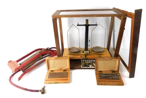 An early 20thC laboratory scales, in glazed dome with metal pans, 41cm high, 46cm wide, 26cm deep, a foot pump, and a cased set of letter stamps. (a quantity)