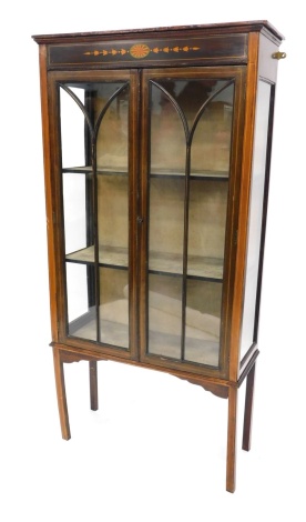 An Edwardian mahogany boxwood strung and painted display cabinet, with a moulded cornice above a frieze decorated with an oval fan, bell flowers, etc., with two astragal glazed doors enclosing a fabric lined interior, on square tapering legs, 76cm wide.