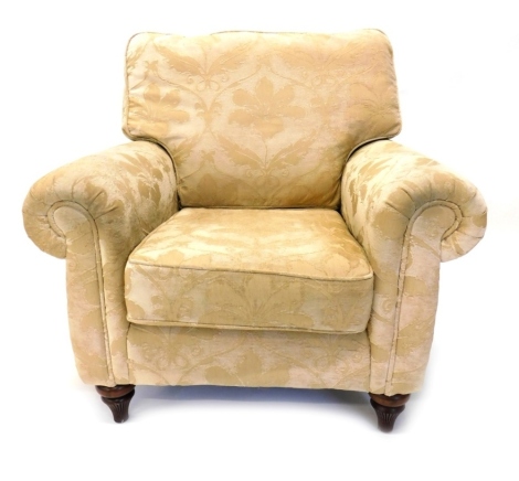 An armchair upholstered in gold damask type fabric, on turned legs.