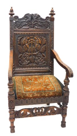 An oak Wainscot chair, the panelled back heavily carved with animal heads, scrolls and flowers, surmounted by floral finials, with carved scroll arm, with a fixed cushion seat, 120cm high.(AF)