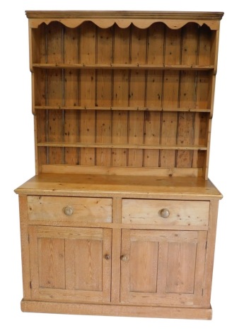 A pine kitchen dresser, the upper section with three shelves set with hooks, the base with two deep drawers above double cupboard revealing shelves, on a block base, 116cm high, 138cm wide, 23cm deep.