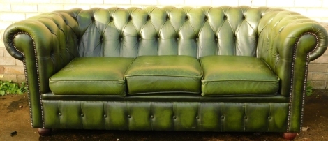 A 20thC green leather three seater Chesterfield Sofa, with button back and three cushions, on bun feet, 76cm high, 185cm wide, 82cm deep.